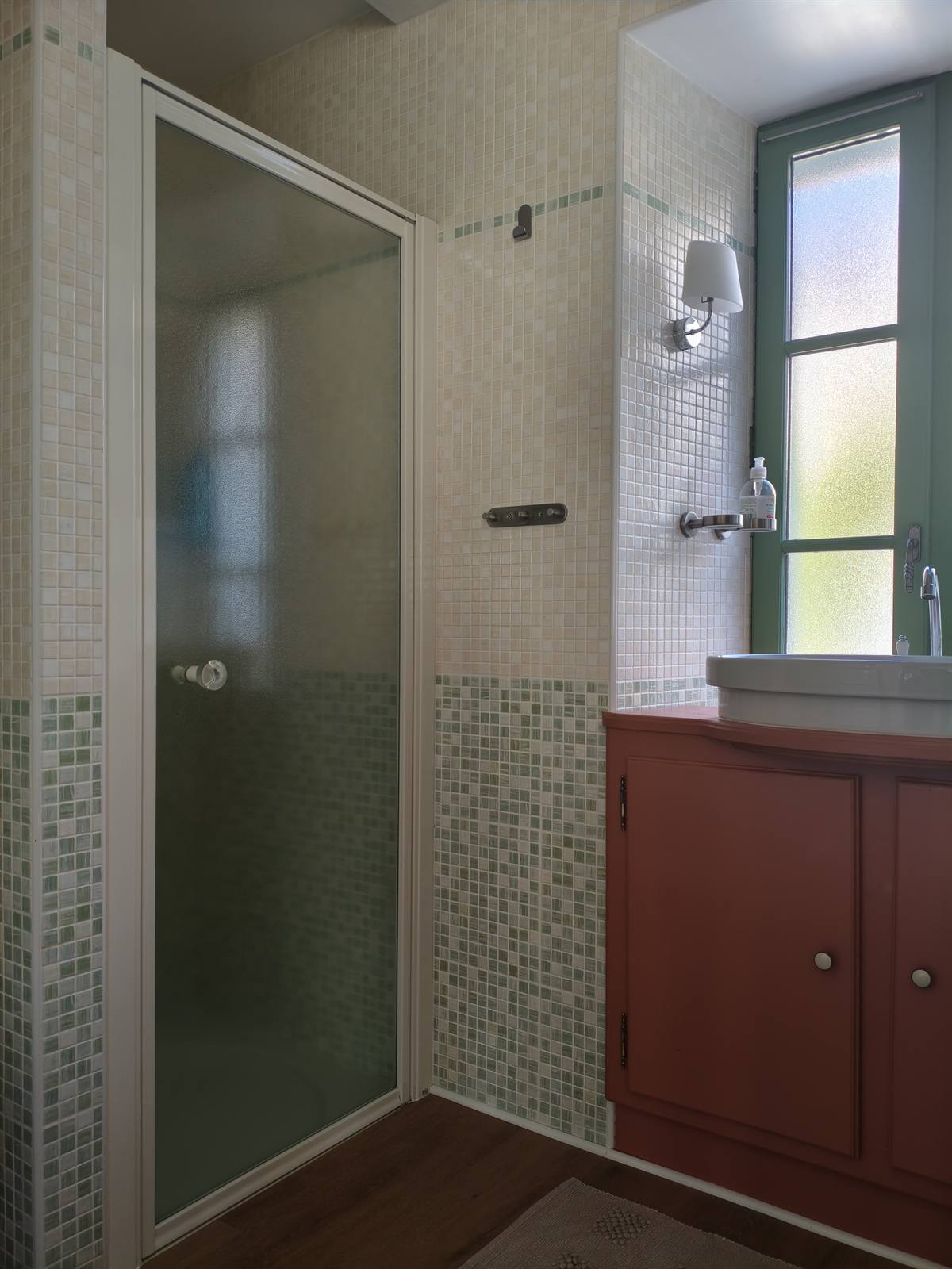Salle d'eau : meuble vasque rouge brique, douche à porte vitrée et mosaïque