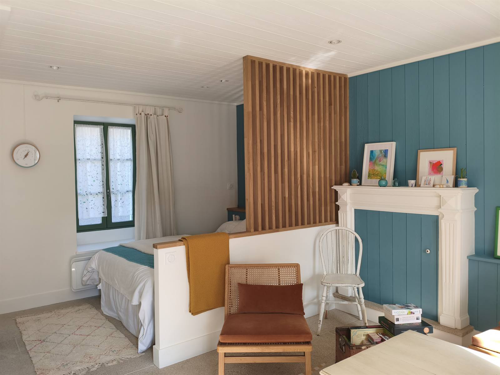Vue d'ensemble : le lit d'appoint derrière le claustra, face à la fenêtre aux volets verts