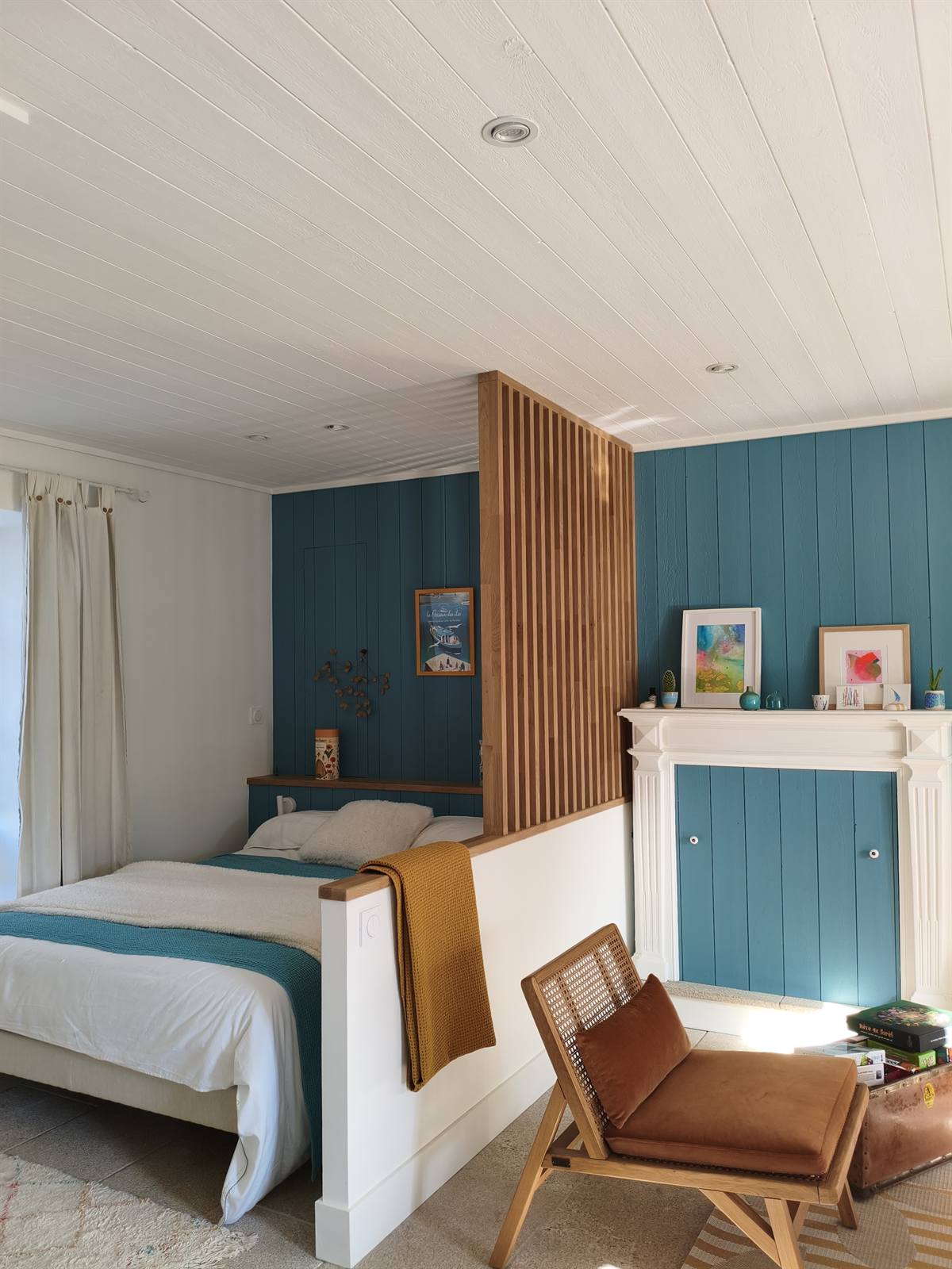 Le lit d'appoint séparé du salon par un muret et un claustra en tasseaux de chêne