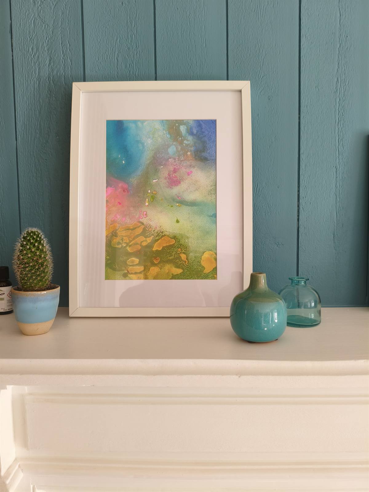 Décoration de la cheminée : aquarelle encadrée, cactus et vases bleus