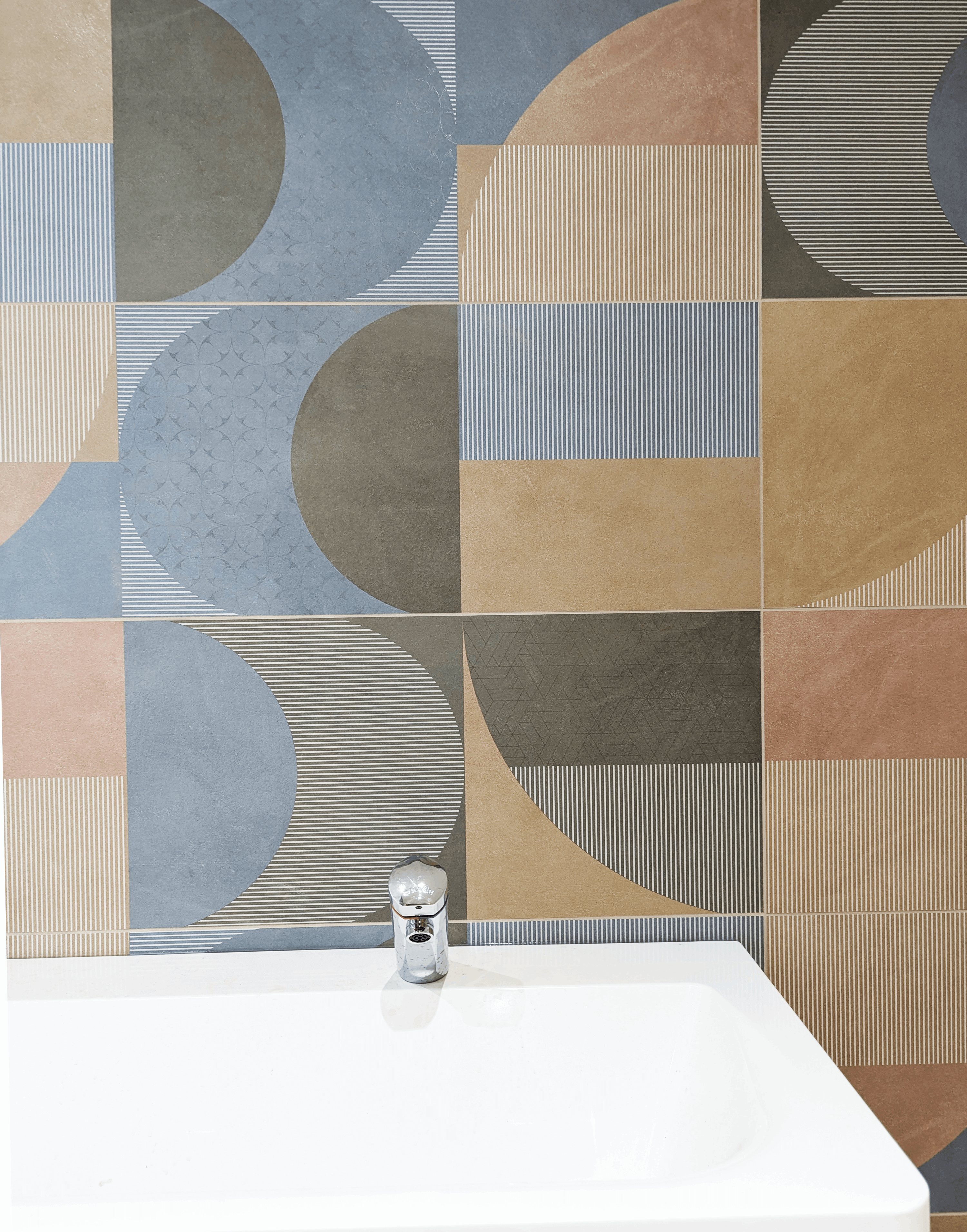 Détail de la faïence à motifs géométriques bleus et ocre au-dessus du lave-mains