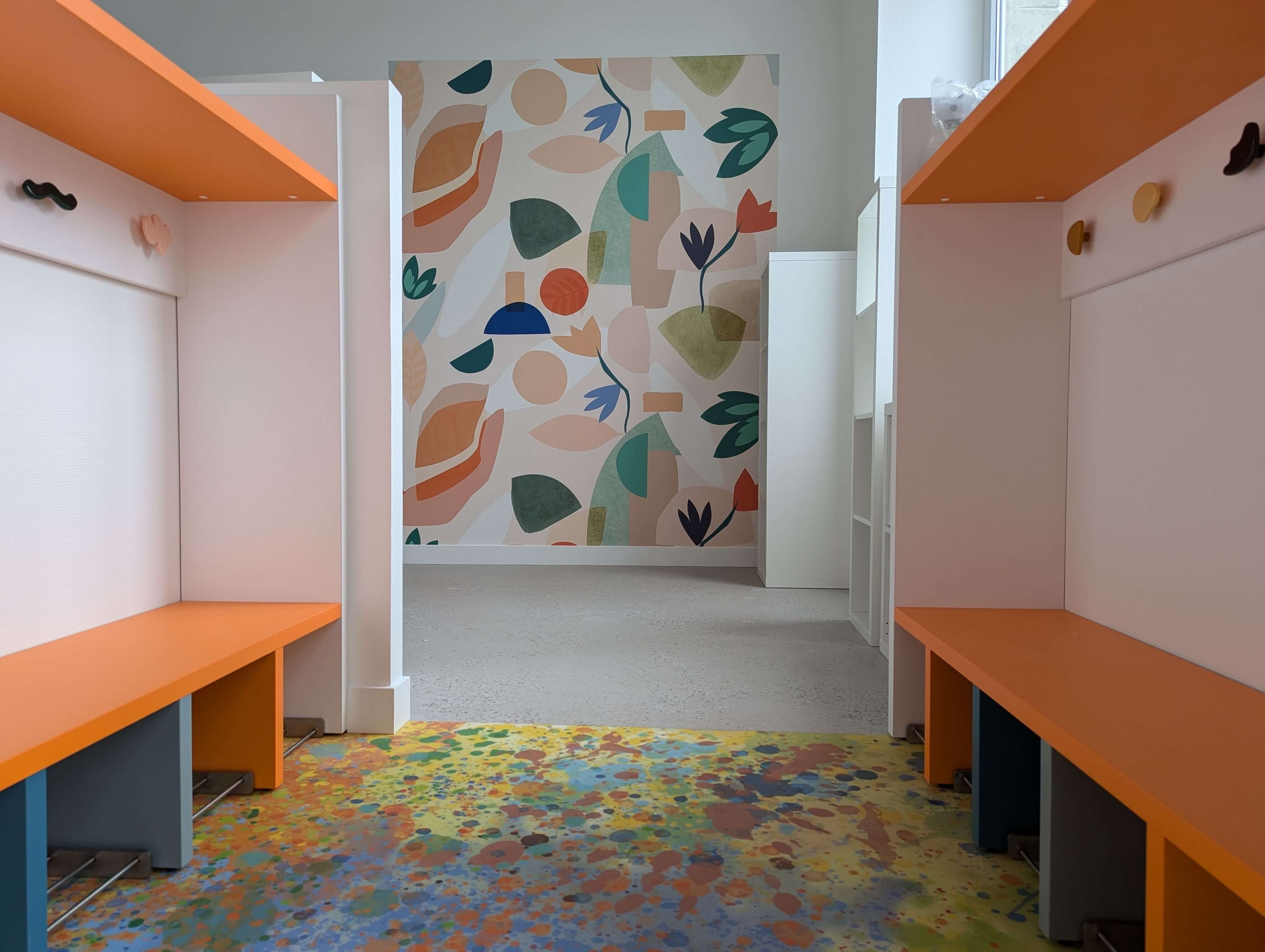 Deux rangées de vestiaires sur mesure encadrant un papier peint panoramique aux formes végétales