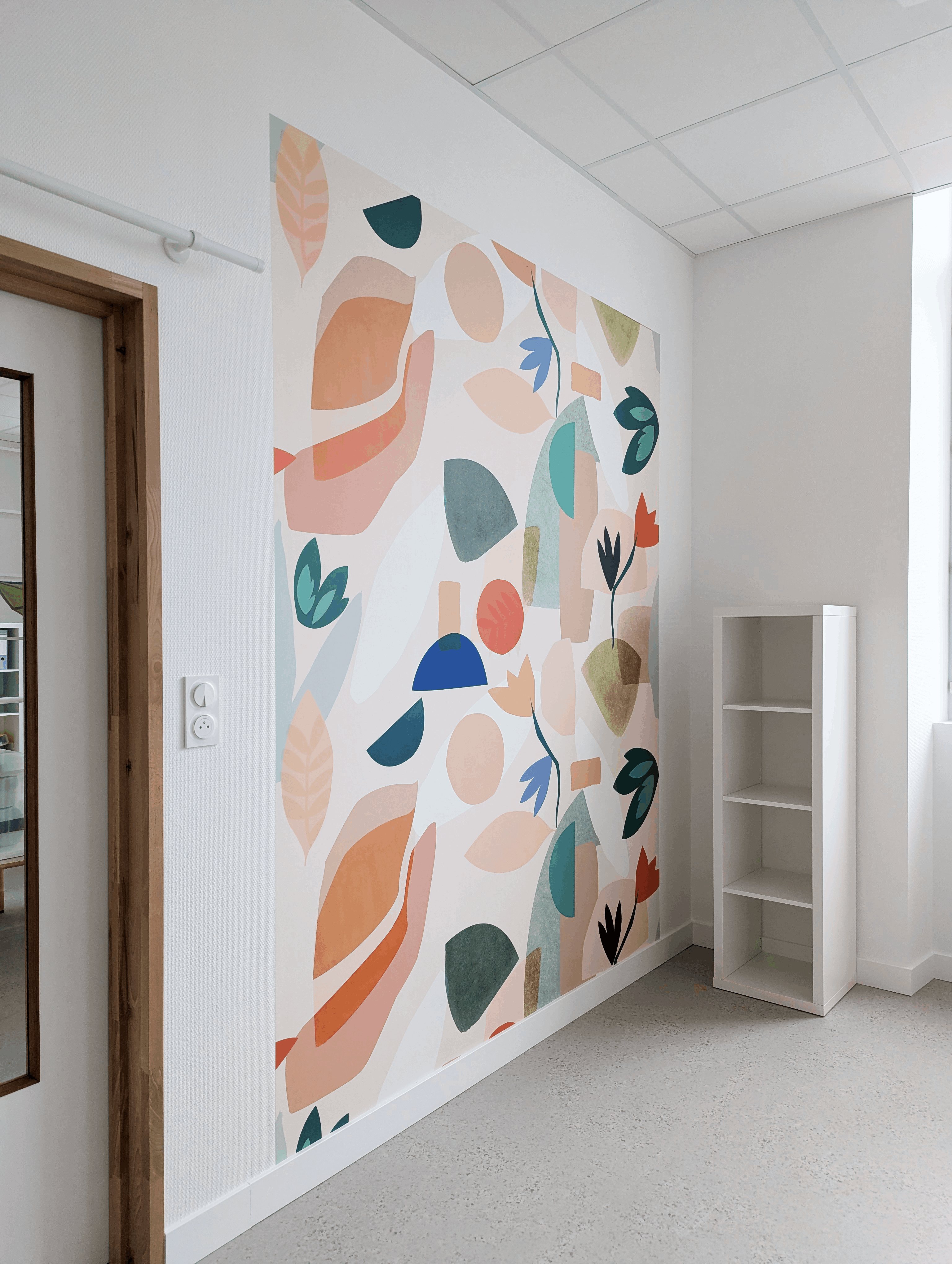Papier peint panoramique aux motifs végétaux et étagère blanche, sur sol clair moucheté