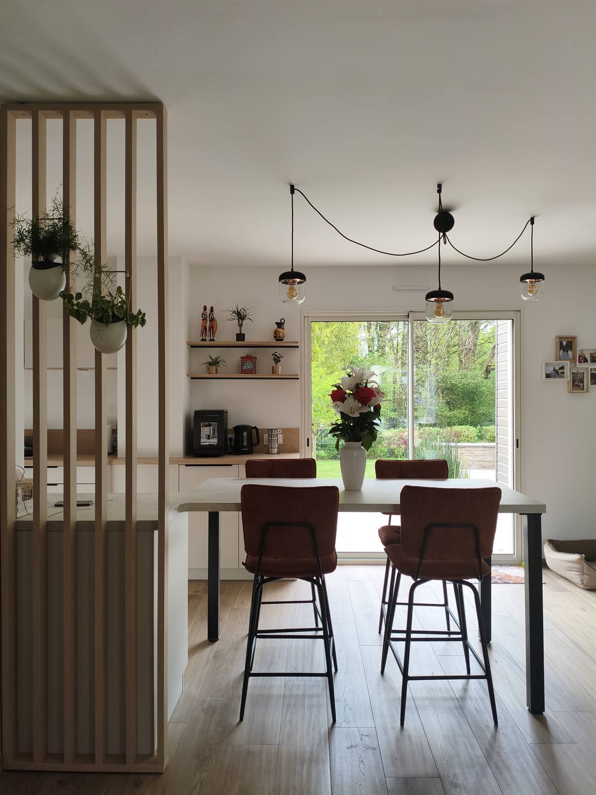 L'espace repas vu à travers le claustra, table haute et baie vitrée donnant sur le jardin