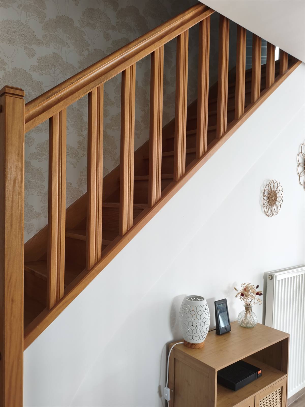 Escalier en bois et papier peint à motif d'arbres dans l'entrée