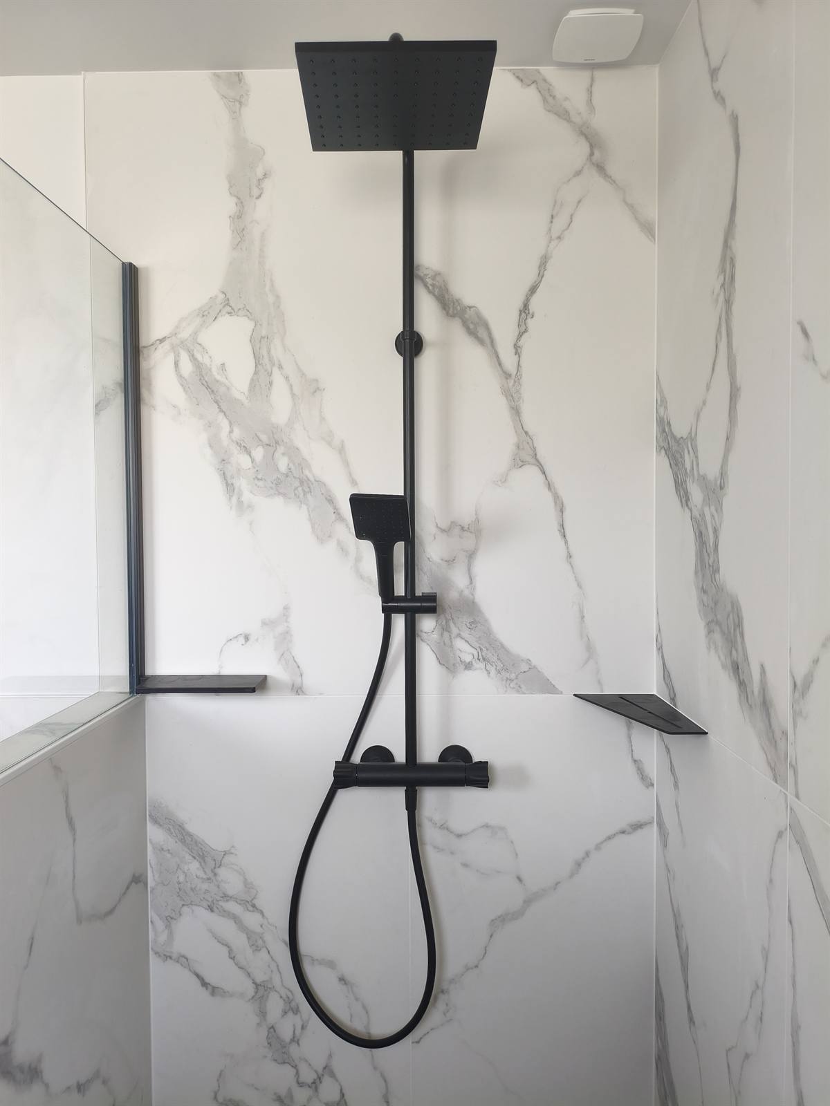 Douche à l'italienne : colonne de douche noir mat et faïence effet marbre blanc