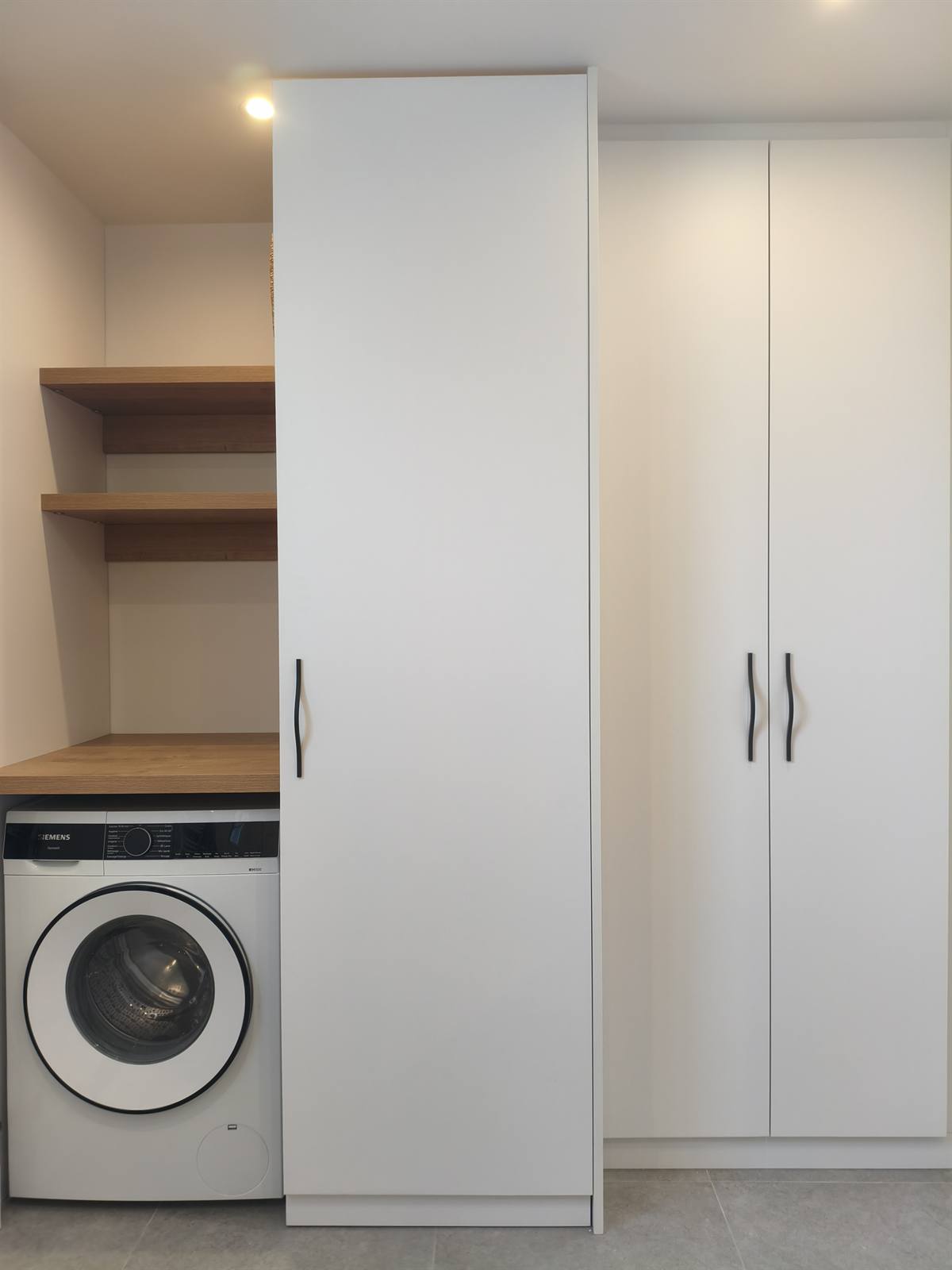 Colonne de rangement sur mesure à côté du lave-linge, étagères en bois et placards blancs