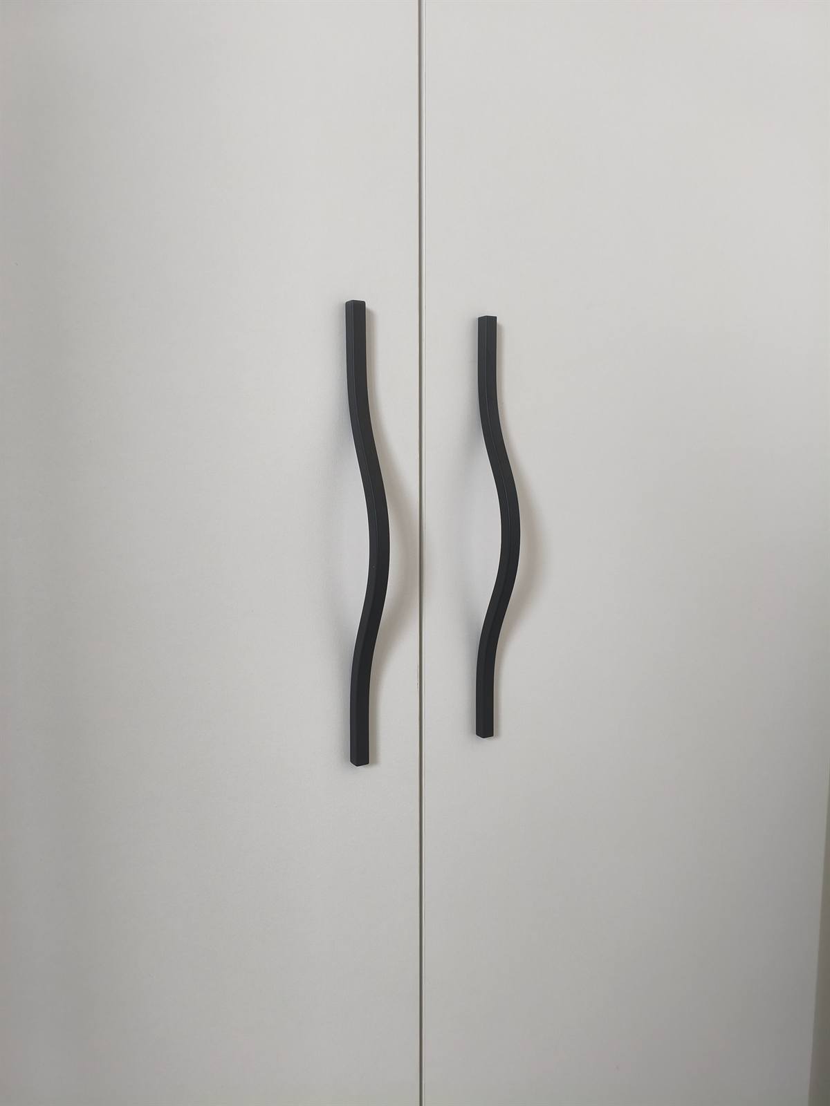 Détail des poignées noires ondulées sur les portes blanches des rangements sur mesure