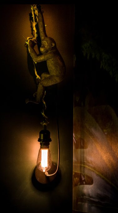 Applique murale : singe doré suspendu à une corde, tenant une ampoule à filament
