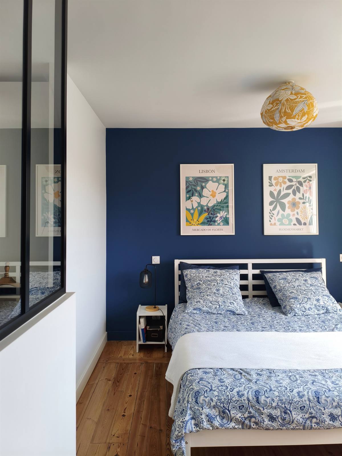 Suite parentale au mur bleu nuit, verrière d'atelier et suspension à motifs jaunes