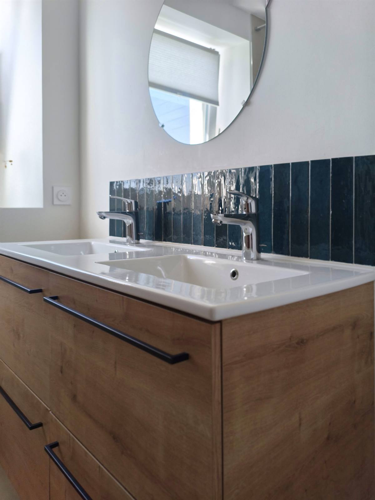Double vasque blanche sur meuble en chêne, zellige bleu canard et miroir rond