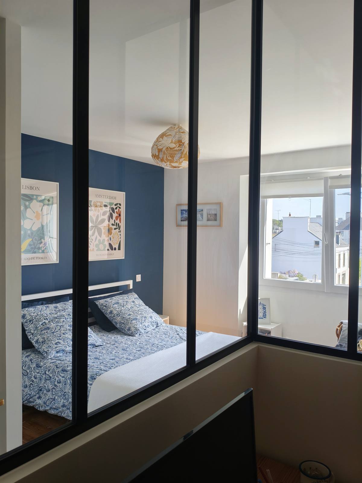 La verrière du bureau, où se reflètent le mur bleu et la fenêtre de la chambre
