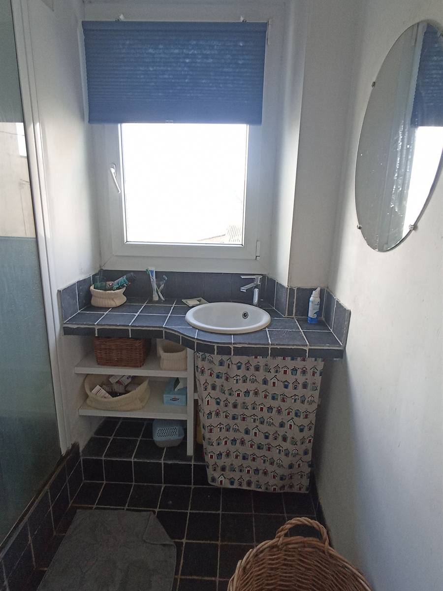 Avant : salle d'eau étroite, lavabo encastré dans un carrelage bleu foncé sous la fenêtre