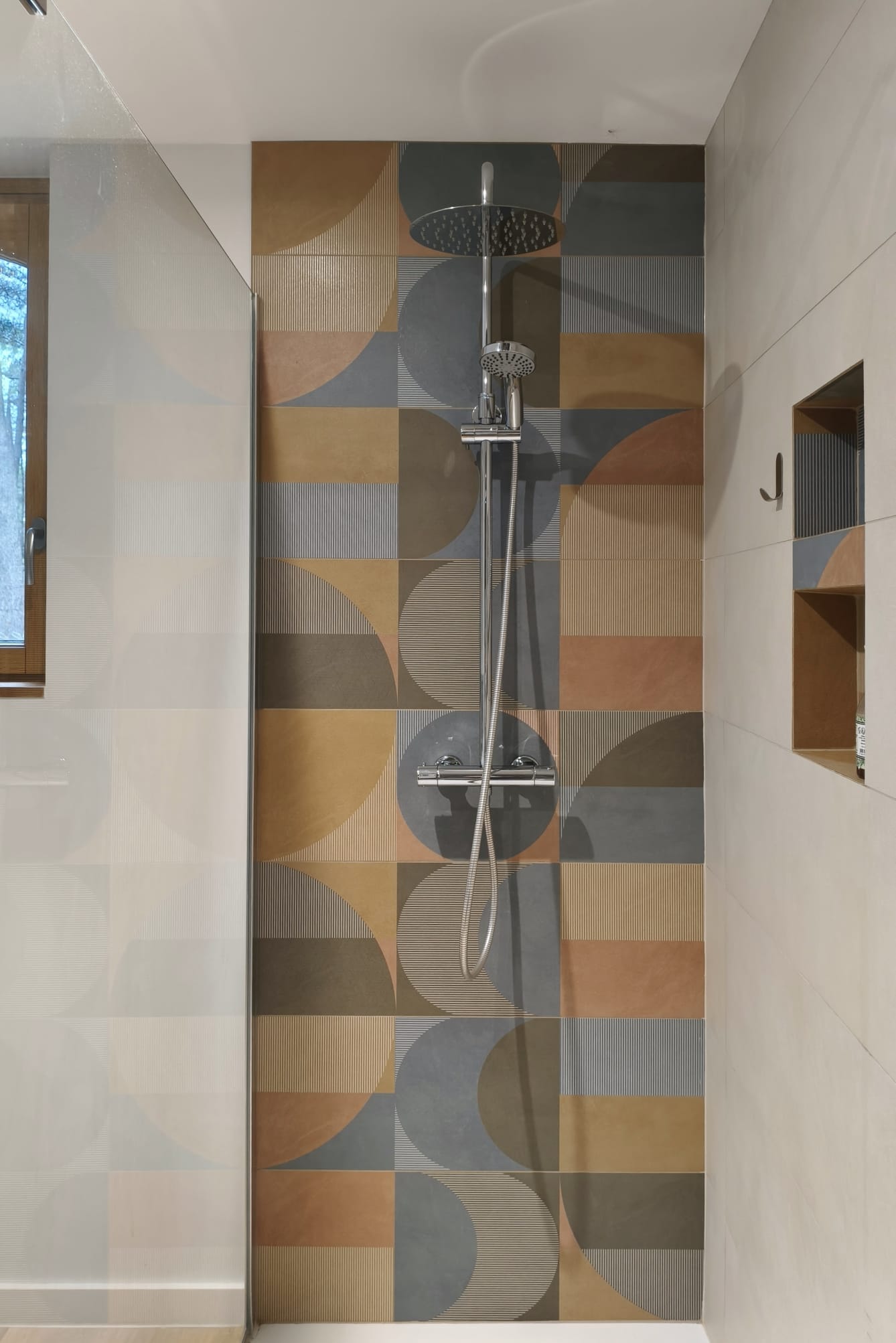 Douche à l'italienne habillée de faïence colorée à motifs géométriques, avec niche murale