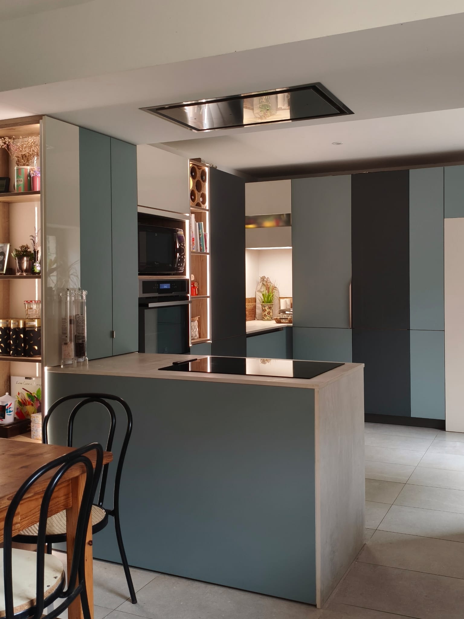 Cuisine avec îlot central, hotte de plafond et colonnes bicolores vert sauge et anthracite
