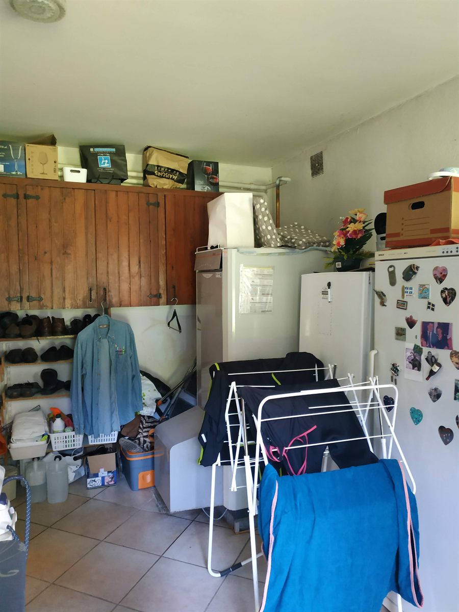 Avant : buanderie encombrée, placards en bois, réfrigérateurs et étendoir à linge