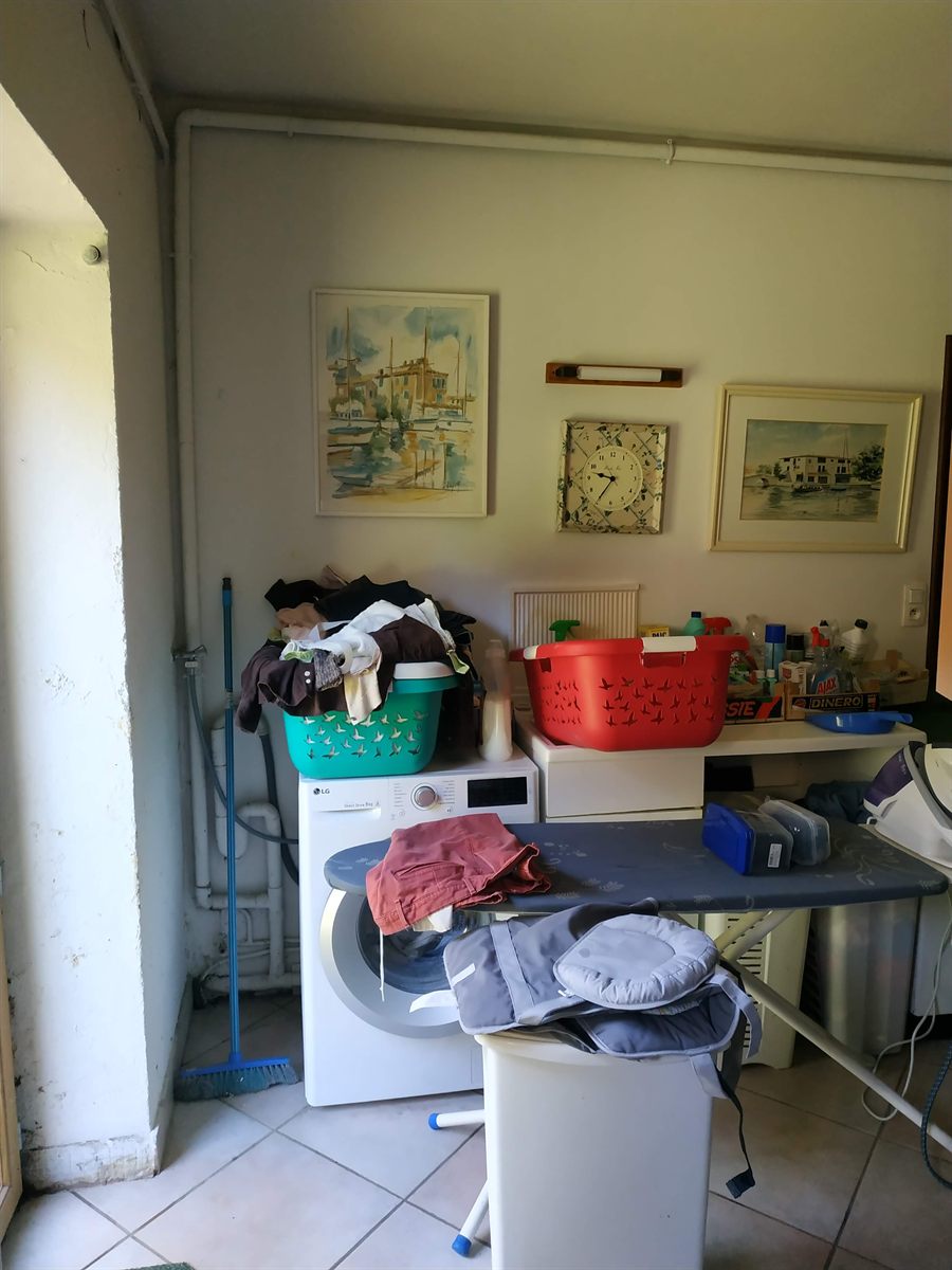 Avant : lave-linge et table à repasser dans la buanderie