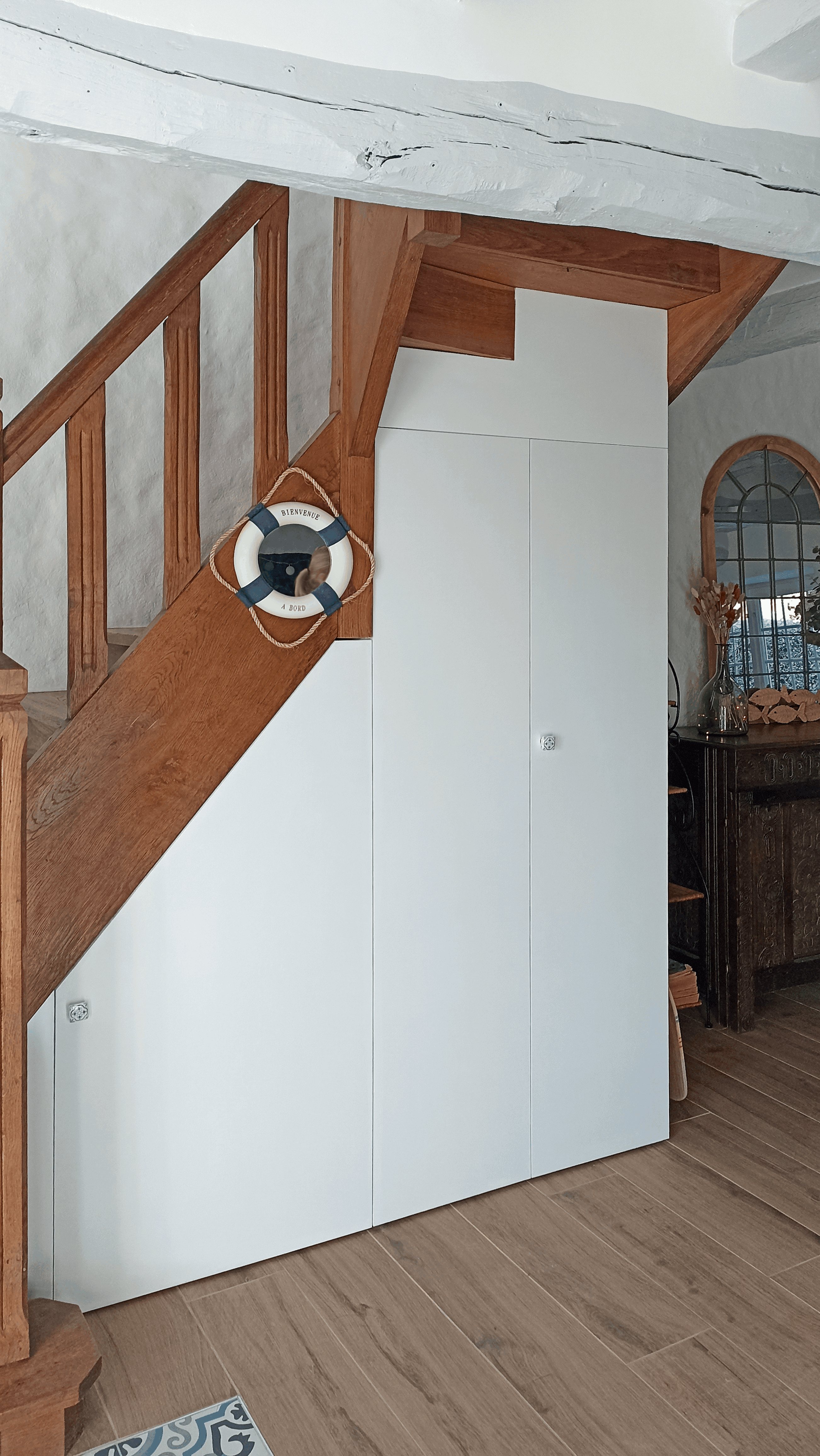 Placard sur mesure blanc aménagé sous l'escalier pour créer du rangement